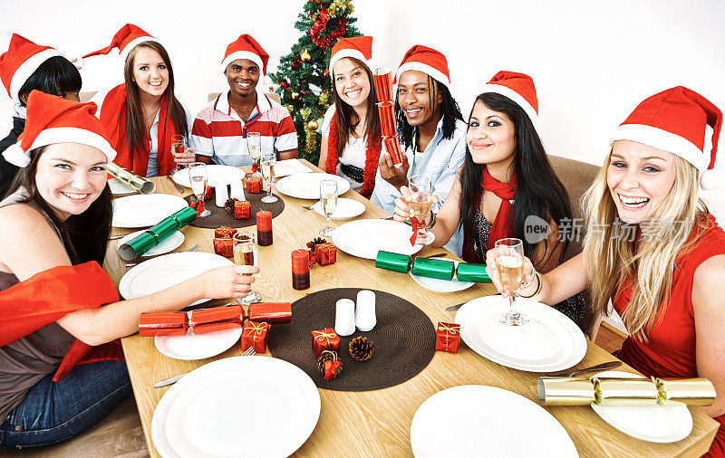 快乐的朋友们围坐在桌子旁，喝着香槟，放着圣诞鞭炮