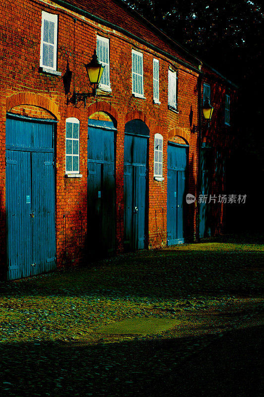 在黑暗中，垂直拍摄了一座砖砌建筑和蓝色的门
