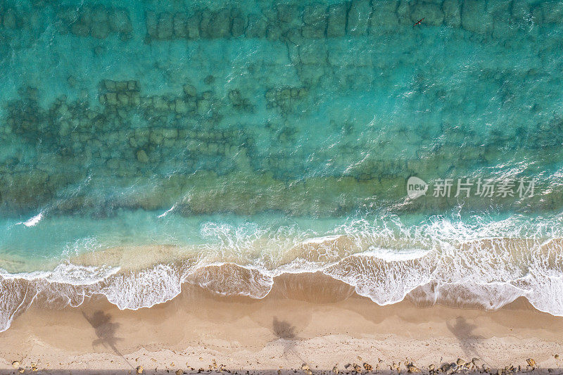 空中鸟瞰图的Aqua海洋与波浪打破白色沙滩与棕榈树的阴影