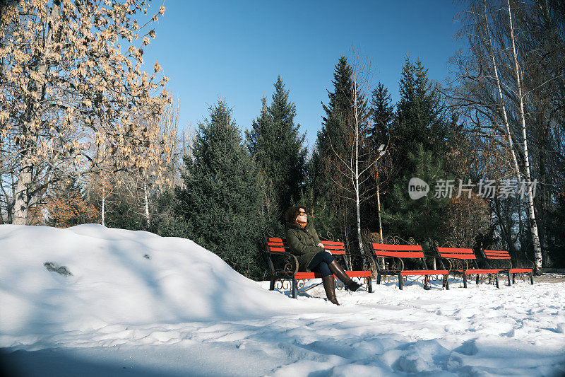 一个女人坐在冬天的公园里