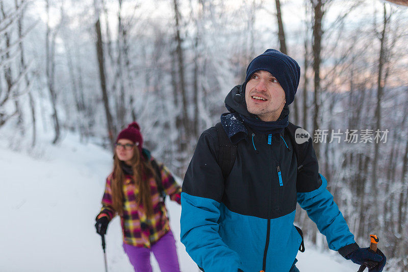 年轻英俊的男性徒步旅行者和他的女性朋友一起爬上雪山