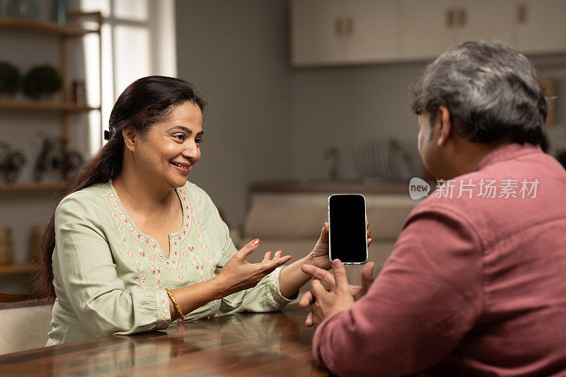 成熟男人向妻子展示智能手机。库存图片
