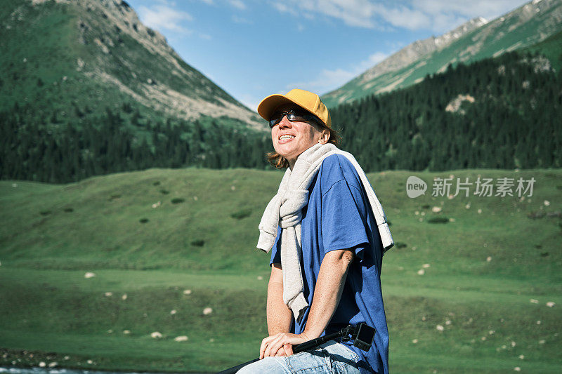 成熟的女游客在美丽的天山峡谷的山河边休息的肖像