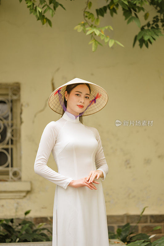 快乐的越南女孩穿着传统的白色敖代服装，戴着越南帽子