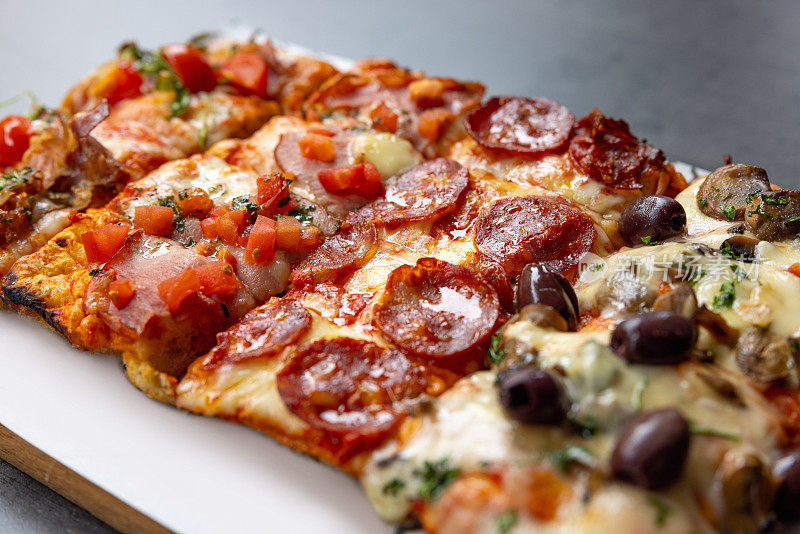 特写在托盘上各种美味的矩形披萨片