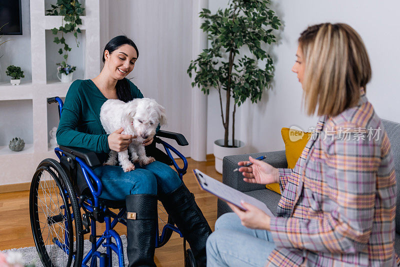 坐在轮椅上的年轻女子在治疗过程中从她的治疗犬和心理治疗师那里找到了值得信赖的盟友