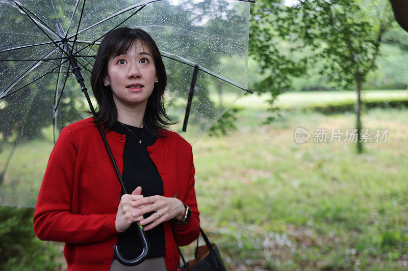 美丽的年轻女子在下雨的公园里放松