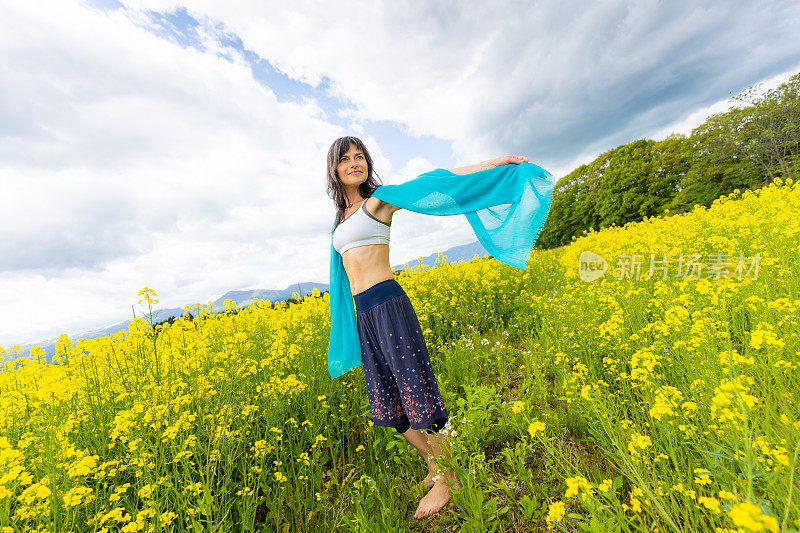 一位妇女在一片黄色的油菜花地里放松和享受户外活动