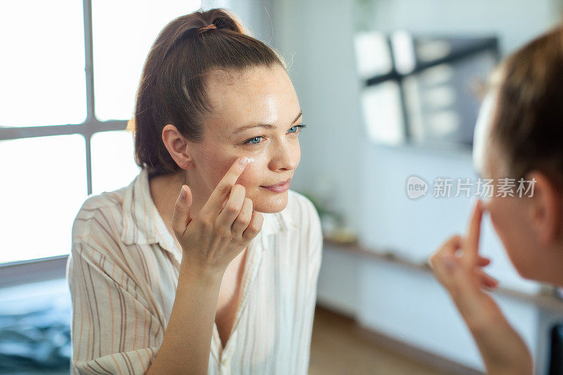 年轻女子在家里对着镜子化妆