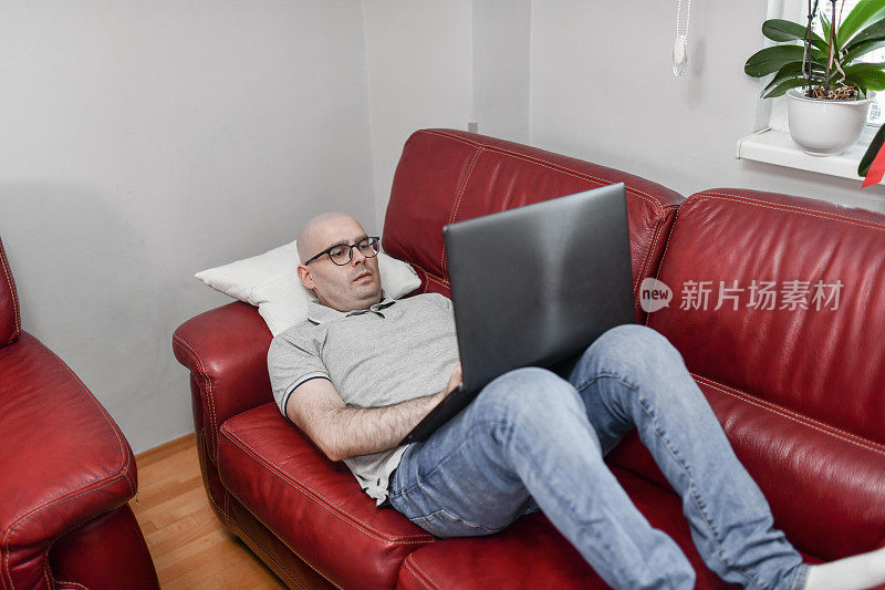 男性癌症患者化疗后躺在沙发上用手提电脑放松休息