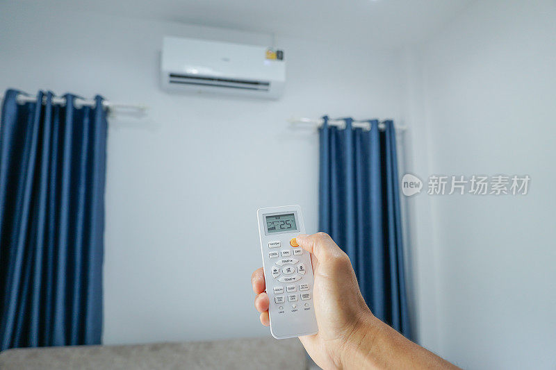 亚洲男人用遥控器打开客厅的空调。简单的能量在家里。