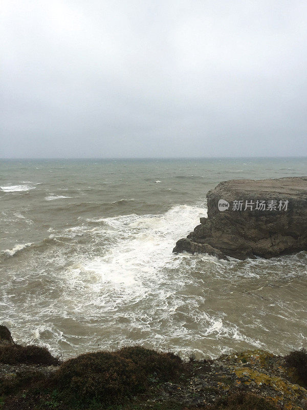 暴风雨天气中的海边悬崖。海岸线岩石，波涛汹涌的大海和多雨的天气背景