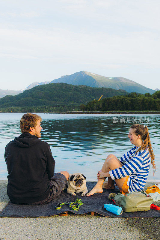 幸福的夫妇与狗欣赏夏天在海上与风景秀丽的山景