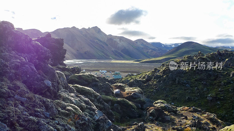 火山岩石露出地面，这是沿着Laugevegur徒步旅行的典型场景，远处有湖和山