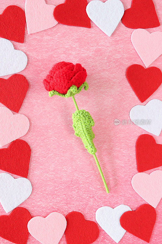 情人节的设计海报框架的形象，由交替红色，粉红色和白色的感觉心形周围钩针玫瑰，斑驳的粉红色背景，抬高的观点，情人节和浪漫的概念