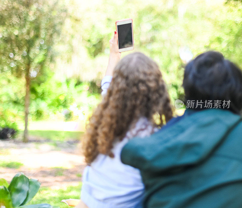 两个不同肤色的大学生在户外用手机自拍