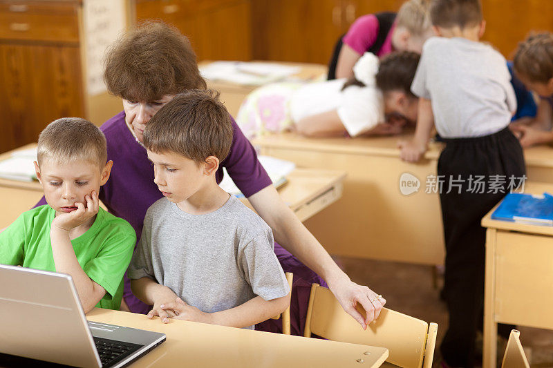 学校的孩子和他们的老师一起看笔记本电脑