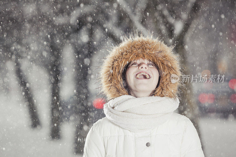 雪下穿着白色夹克的漂亮少女