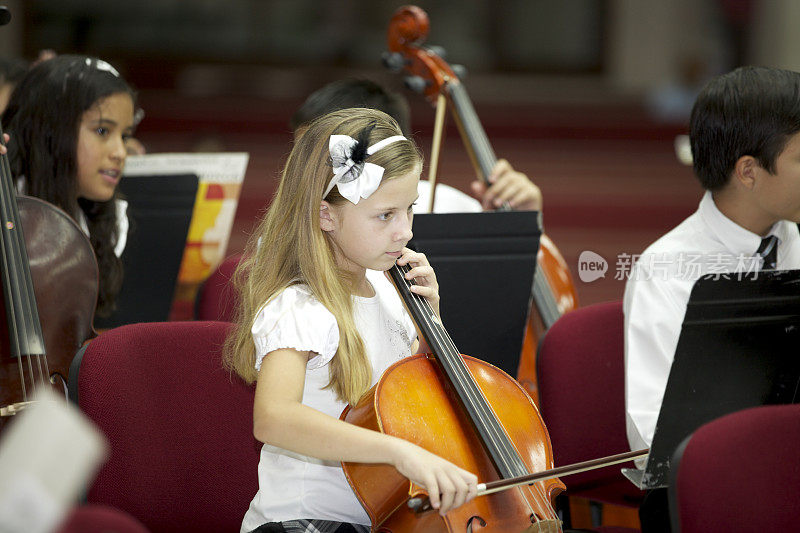 年轻的大提琴演奏家在音乐会上与管弦乐队一起演奏。
