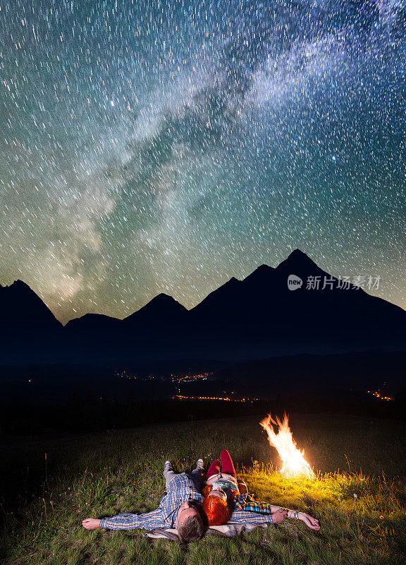 在美丽的星空下，游客们躺在篝火旁