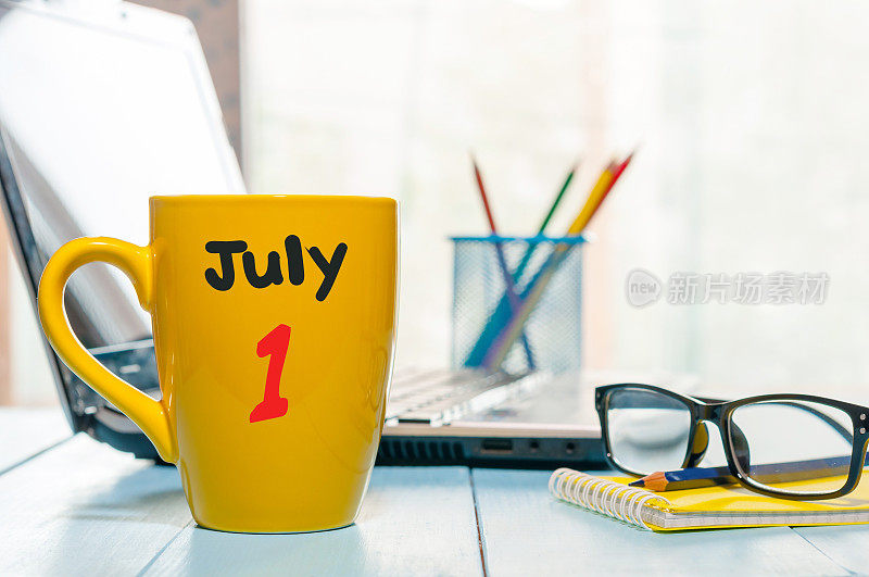 7月1日。月1日，彩色日历上的黄色早上咖啡杯在商务工作场所背景。夏天的概念。文本空白