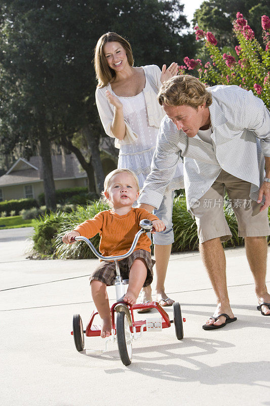 爸爸帮孩子骑三轮车，妈妈在鼓掌