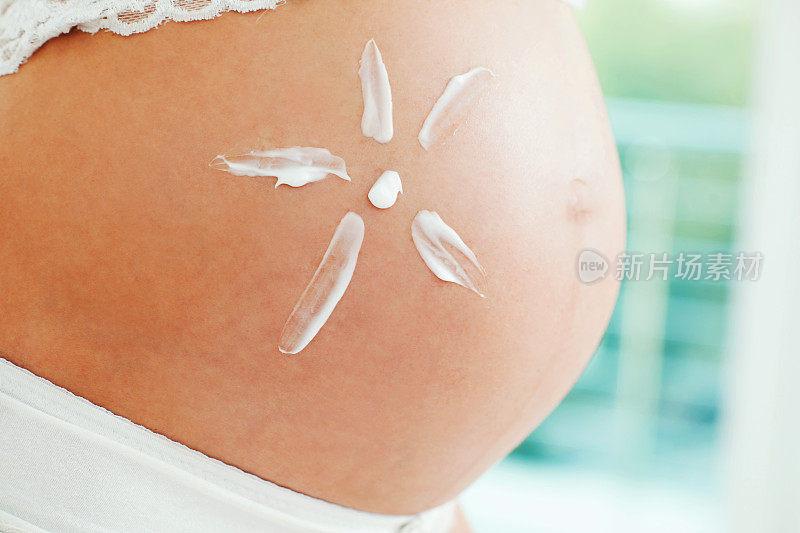 一个怀孕的腹部与奶油的特写。