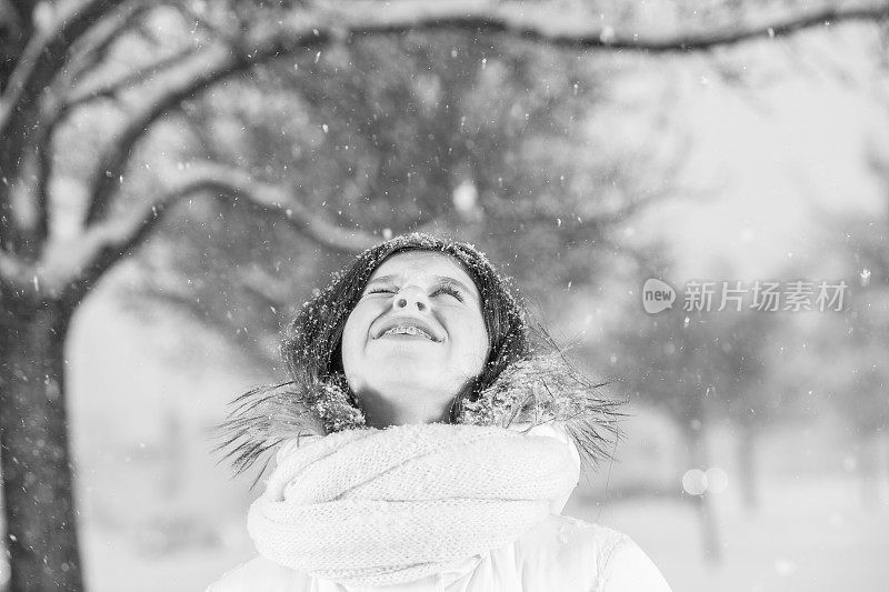 雪下穿着白色夹克的漂亮少女