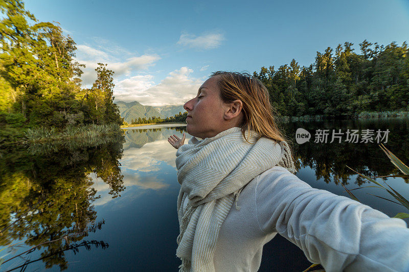 女性在湖边放松，倒影在水面上