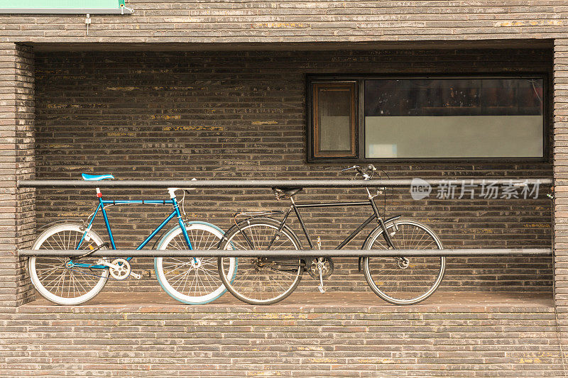两辆自行车停在有砖墙的露台上