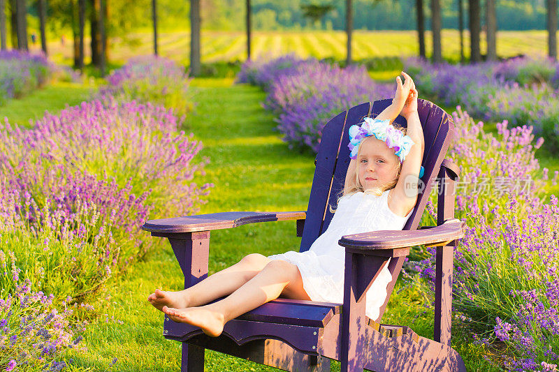 小女孩坐在薰衣草地里的椅子上