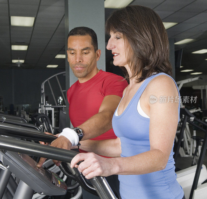一名妇女在健身俱乐部的跑步机上锻炼。