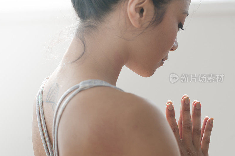 年轻的纹身女子在祈祷姿势