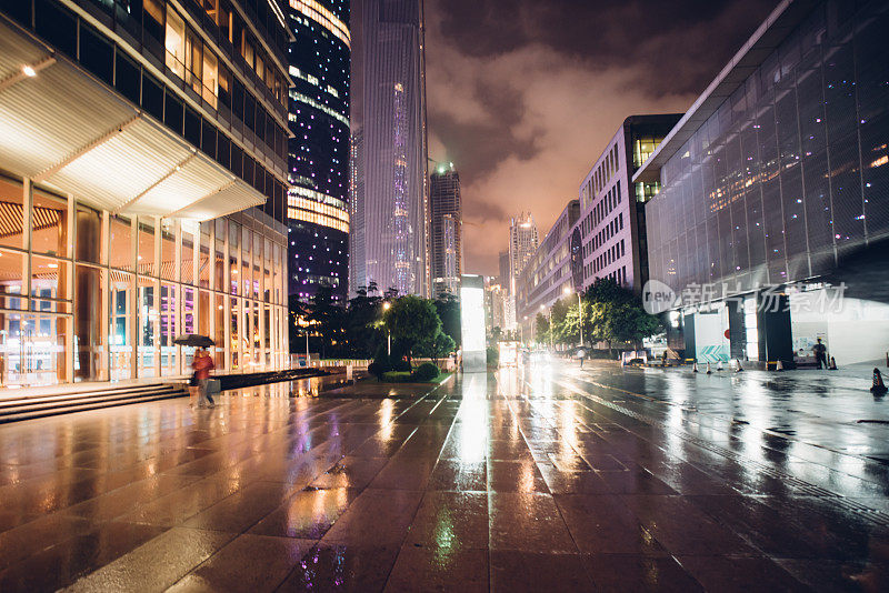 人们在雨中行走，在城市的夜晚