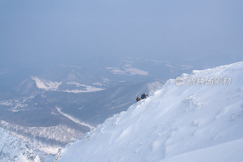 三个冰攀登者正在攀登一座山峰的顶峰