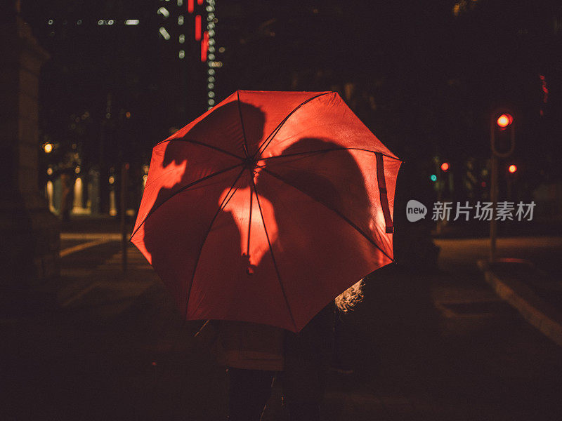 一对情侣在镇上的红伞后面接吻