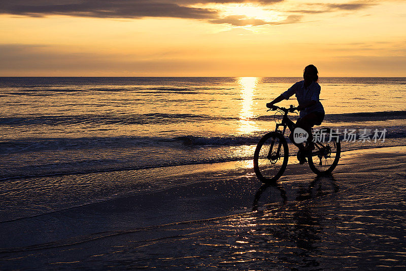 在海滩上骑自行车的女人