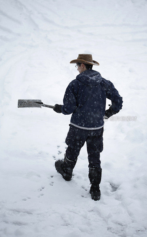 加拿大下雪时，一个年轻人拿着铲子