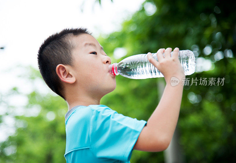 亚洲小男孩在户外喝水