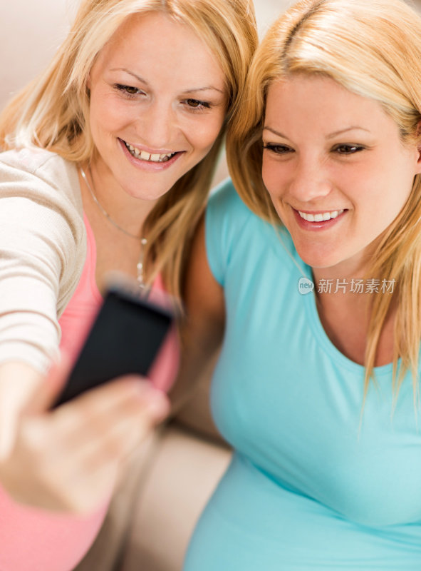 年轻快乐的孕妇用手机自拍。