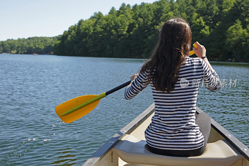 一个女孩在夏日的湖中划着独木舟