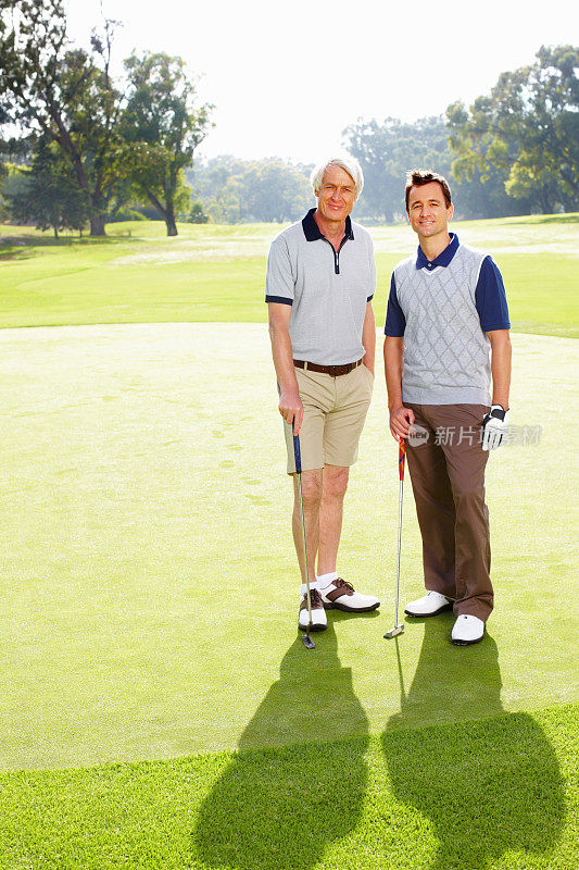 父亲和儿子站在高尔夫球场上