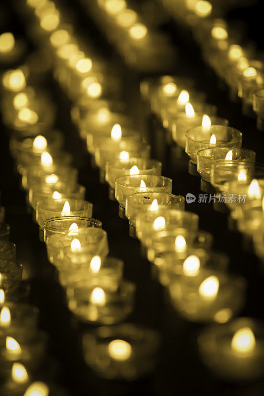 在黑暗的教堂里，成排的蜡烛燃烧着
