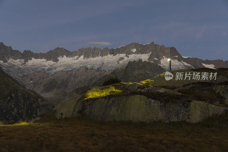 一个带着大灯的阿尔卑斯人站在瑞士阿尔卑斯山令人叹为观止的山景中