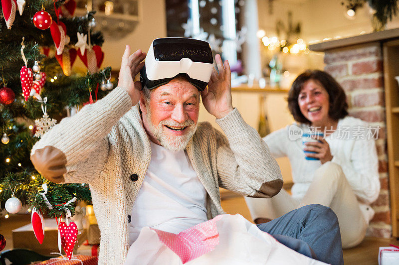 一对老年夫妇戴着VR眼镜站在圣诞树前。
