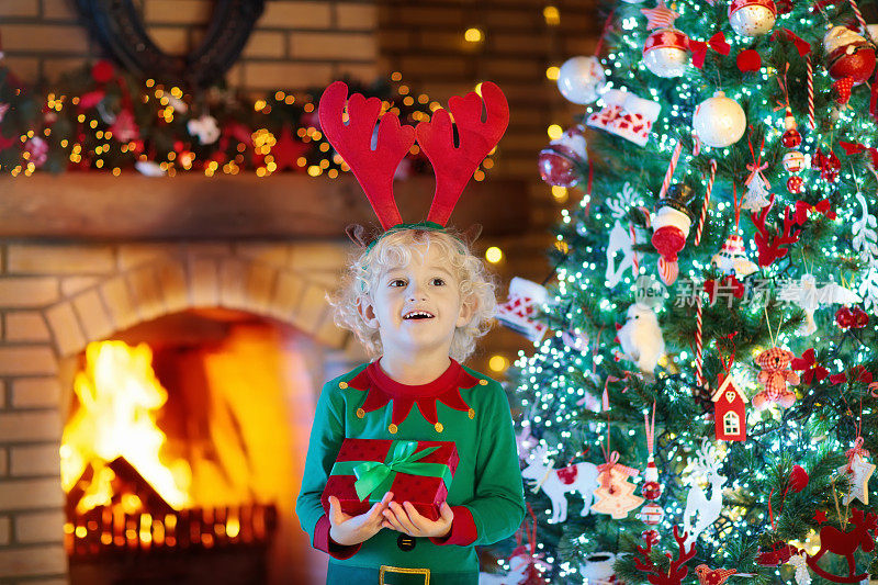 孩子在圣诞树和壁炉在圣诞夜