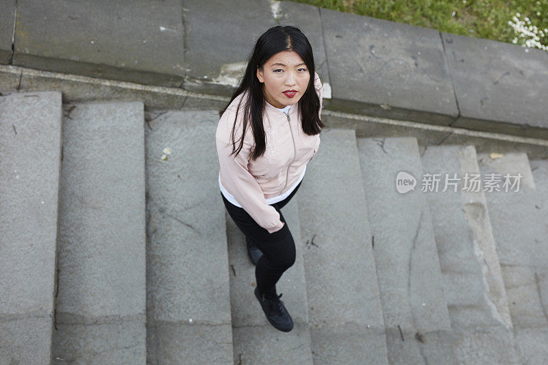 亚洲女人在楼梯上摆姿势。城市景观。高角度视图