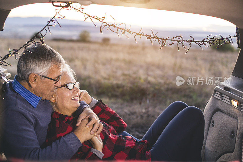 一对老年夫妇在徒步旅行前坐在敞篷汽车后备箱里