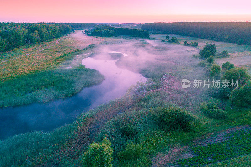 鸟瞰图乡村和河流在清晨薄雾。树木沿着河。日出前的时间。从上面的观点
