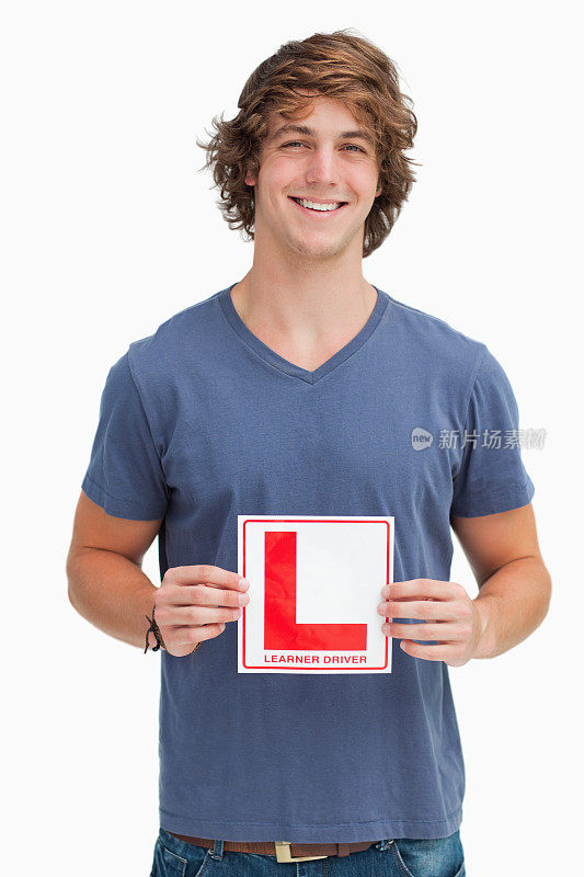 微笑的年轻人拿着一个初学者驾驶标志